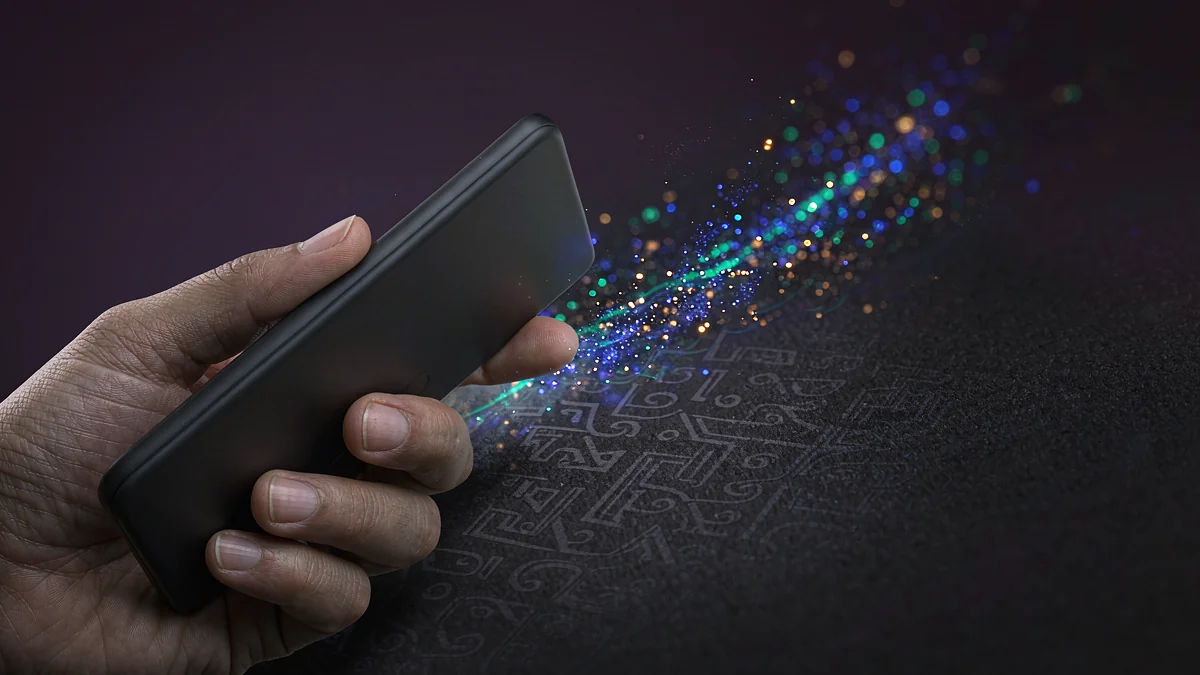 Hand holding a smartphone with colorful light particles